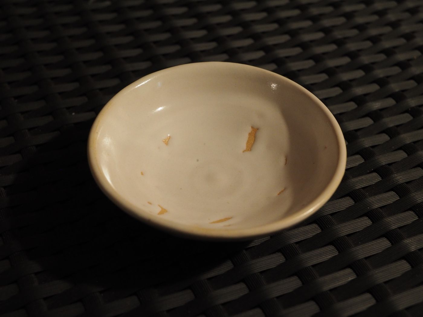 Photo de la coupelle, couleur blanc cassé, on voit que l'email est mal réparti et laisse voir l'argile par endroit